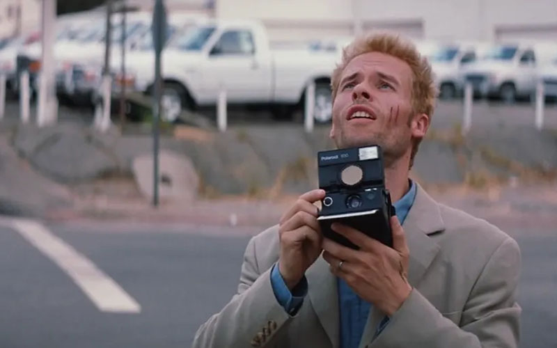 Guy Pierce holding polaroid camera in memento