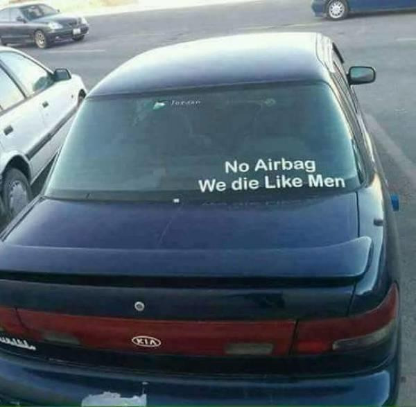 Photograph of the backside of a blue sedan. Visible on the rear windshield is a bumper sticker that says,'No Beta, We Die Like Men', all in white text