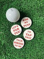 Four circular, flat, pieces of wood used as golf ball markers. Each one has a funny line of text on them; one says 'kiss my putt', another says, 'let's par-tee', another says, 'I'd tap that', and the last one says, 'talk birdie to me'.