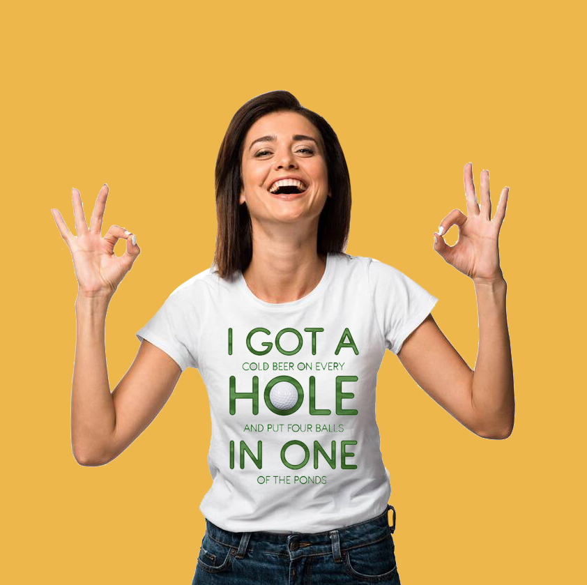 A woman wearing a white graphic tee shirt. It has the words 'I got a cold beer on every hole and put four balls in one of the ponds'.